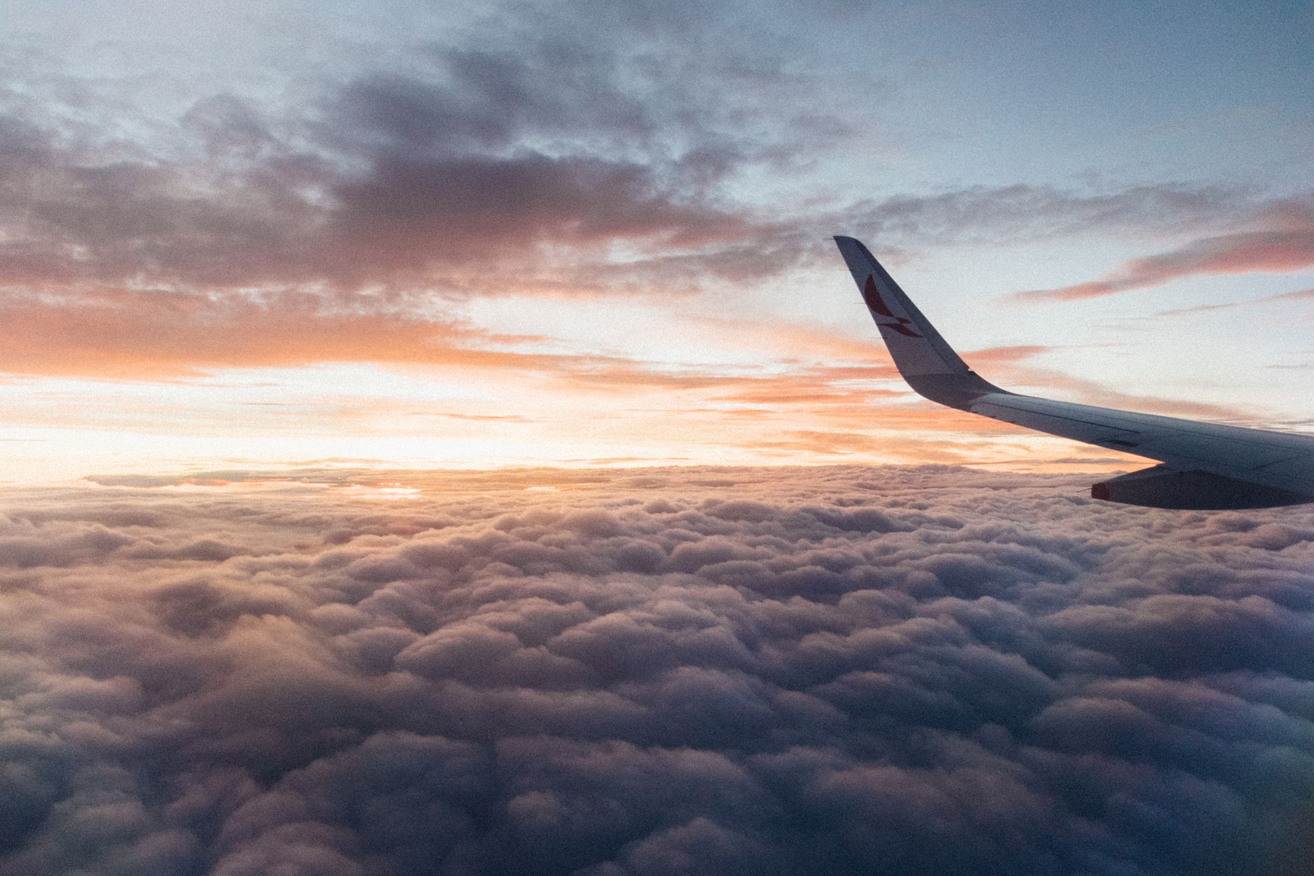 An airplane wing above a sea of golden sunset clouds